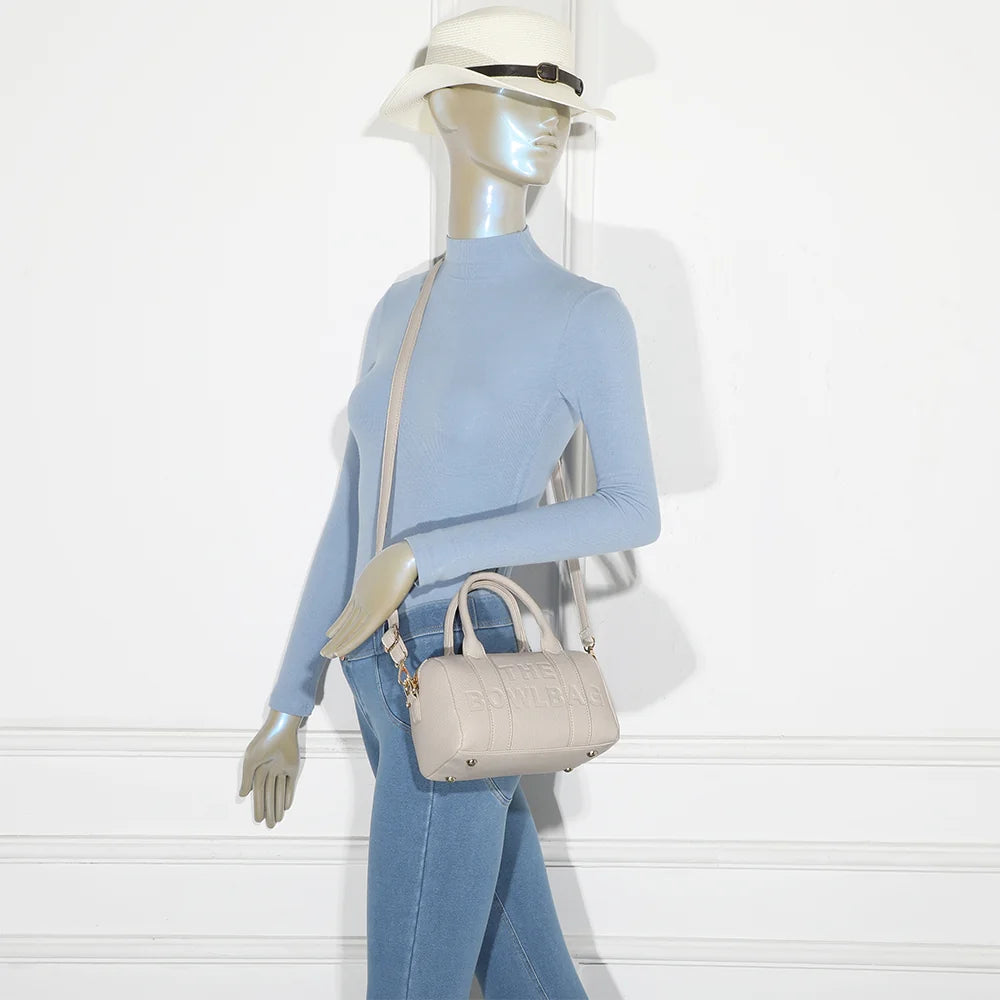 Bowlbag mini beige porté par une femme, à la main ou avec sa bandoulière amovible et réglable – réf. R-1995