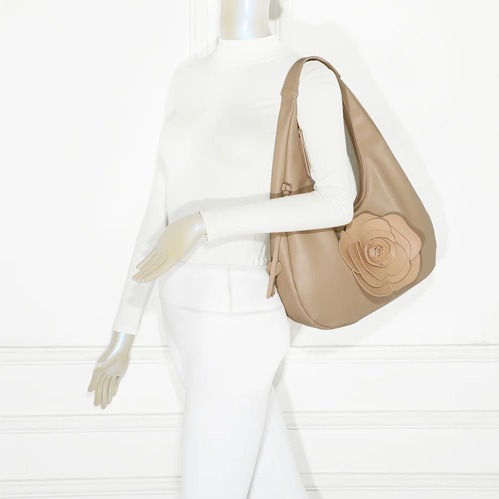 Sac Fleur de Lune taupe porté à l’épaule par une femme, rose en relief bien visible – réf. G-7494