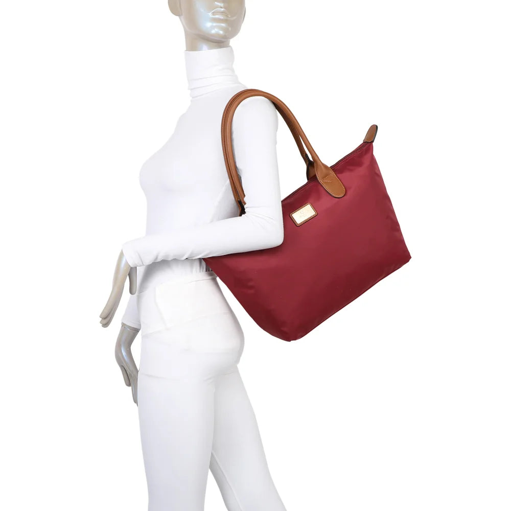 La Balade Medium bordeaux portée par une femme : un sac cabas au format medium avec deux anses marron – réf. Z-03
