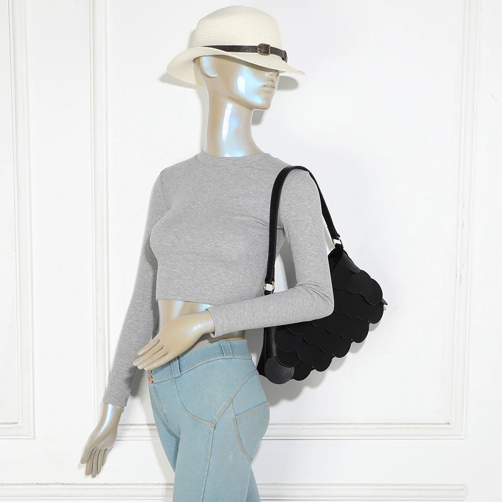 Sac La Écaille noir porté à l’épaule par une femme, anse courte et détails dorés – réf. G-7517