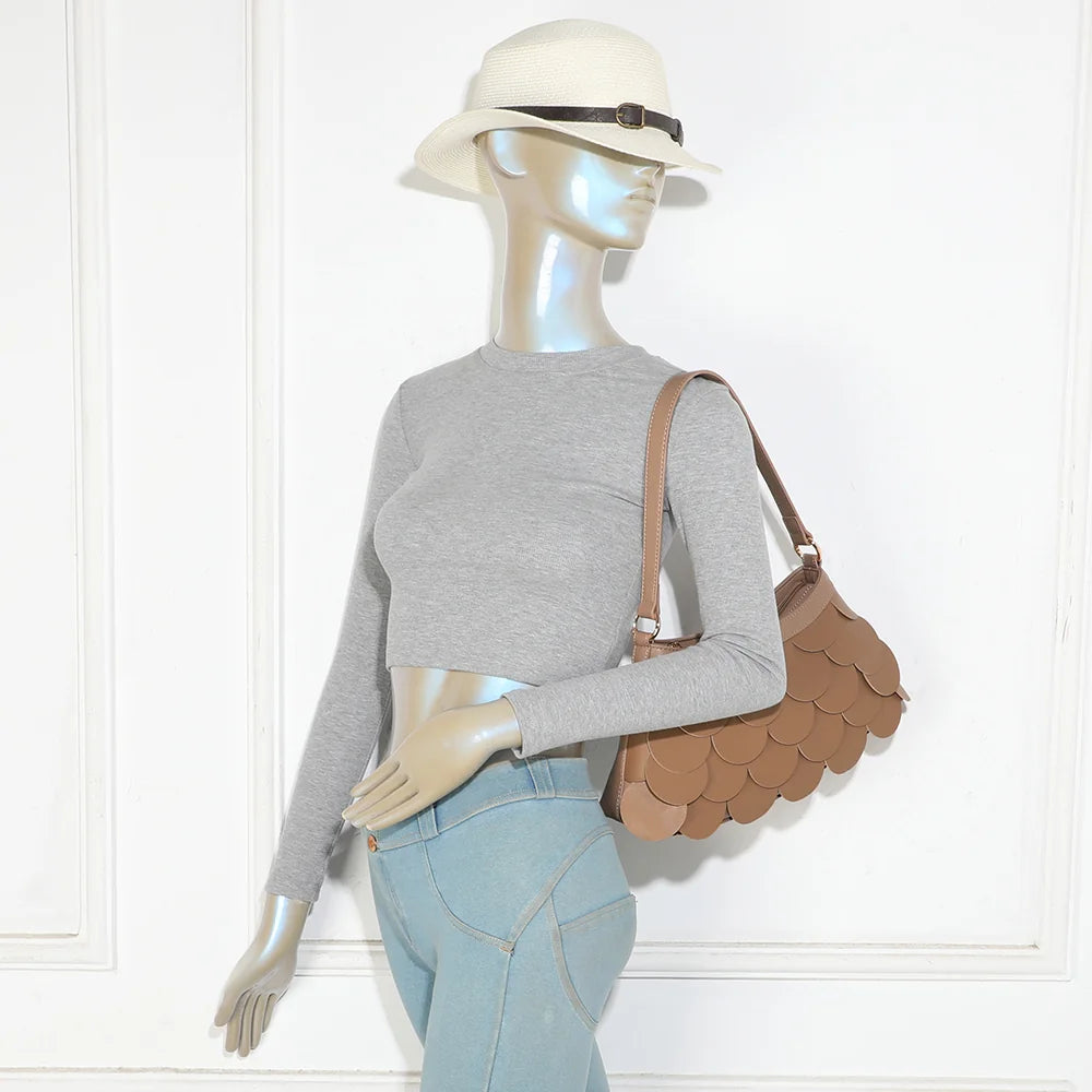 Sac La Écaille taupe foncé porté à l’épaule par une femme, anse courte et détails dorés – réf. G-7517