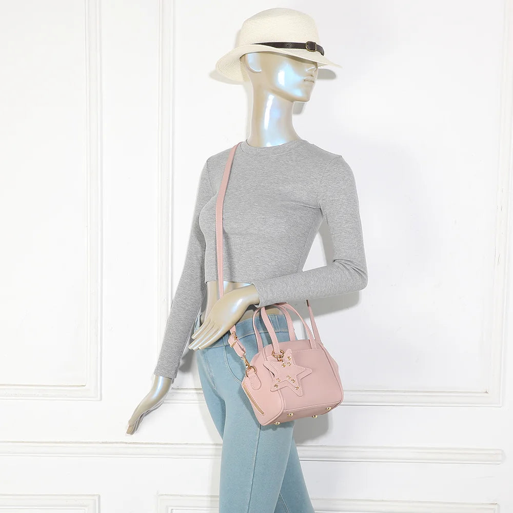 Mini sac La Féerie rose foncé porté par une femme, à la main ou avec sa bandoulière amovible – réf. R-2052