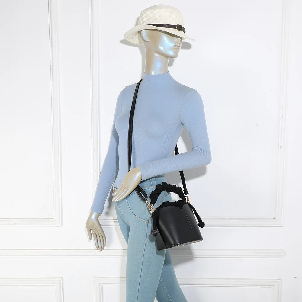 Sac La Nuvia noir porté par une femme, à la main par sa poignée froncée ou en bandoulière – réf. DQ-8727