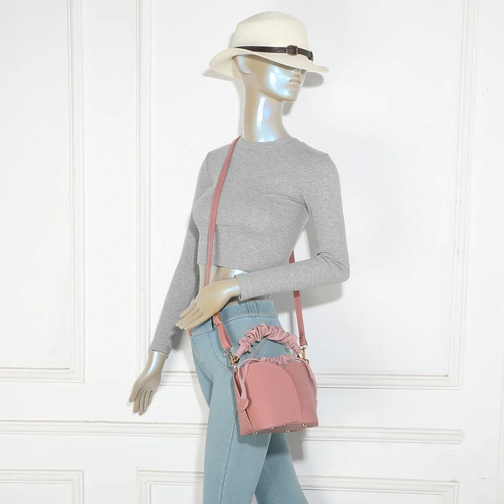 Sac La Nuvia rose foncé porté par une femme, à la main par sa poignée froncée ou en bandoulière – réf. DQ-8727