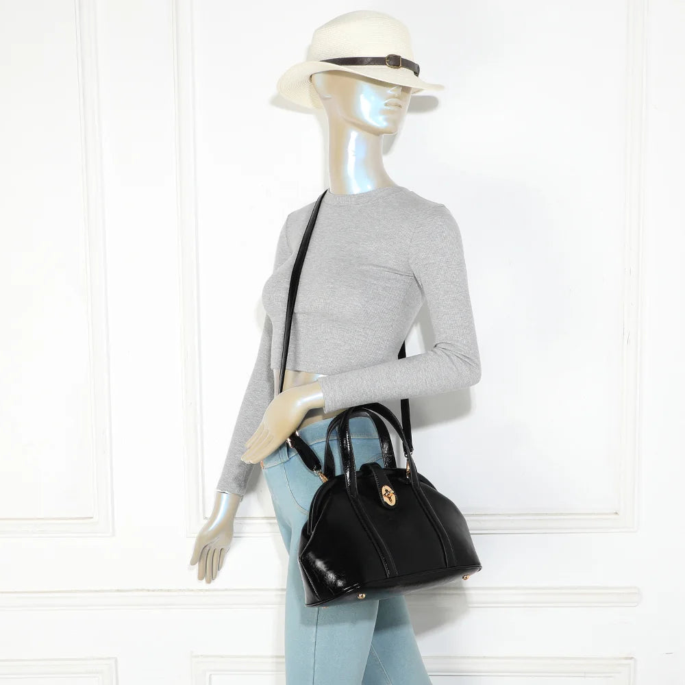 Sac La Parure noir porté par une femme, tenu à la main par ses deux anses surpiquées – réf. R-2065