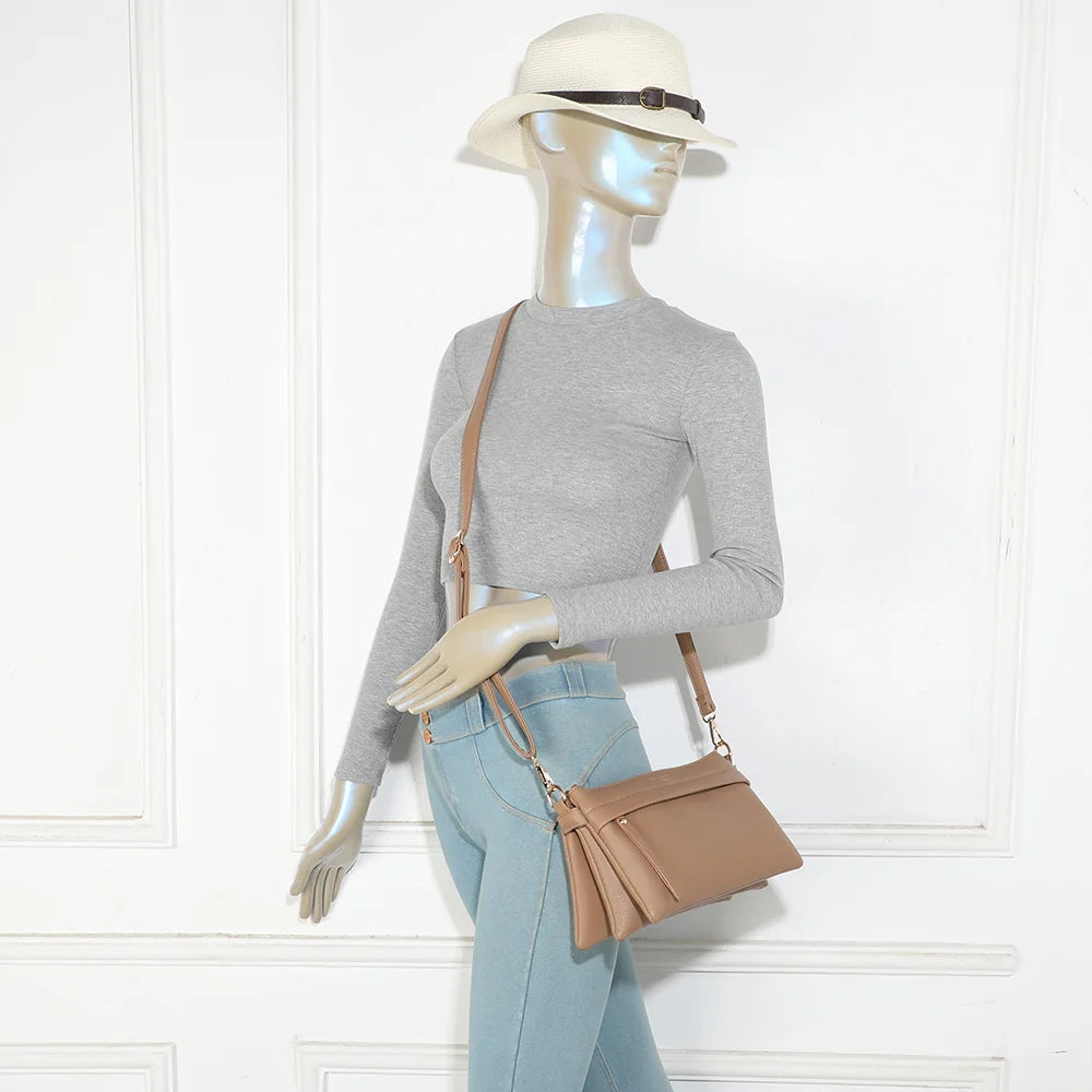 Sac bandoulière La Vélane taupe foncé porté en travers du corps par une femme, bandoulière réglable – réf. A-9176