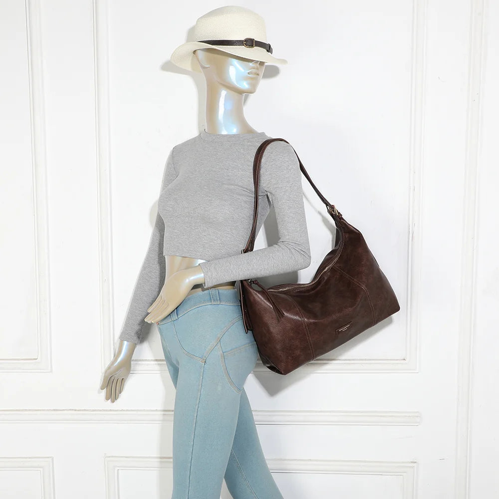 Sac Le Brumaire marron foncé porté à l’épaule par une femme, anses ajustées par boucles dorées – réf. JC-53012