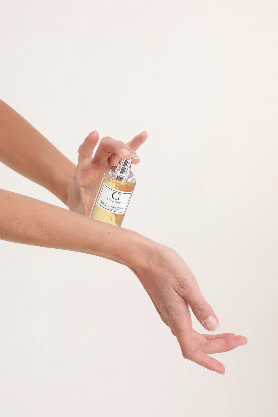Vaporisation de l'eau de parfum Mula Secret sur un poignet, flacon de 50 ml à bouchon noir