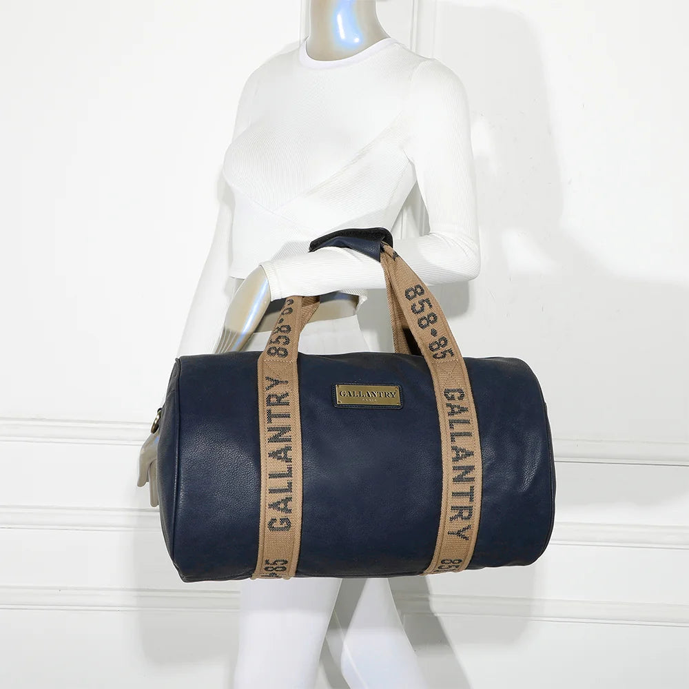 Sac de voyage Polochon bleu marine porté à l’épaule par une femme grâce à sa bandoulière amovible – réf. Z-83049