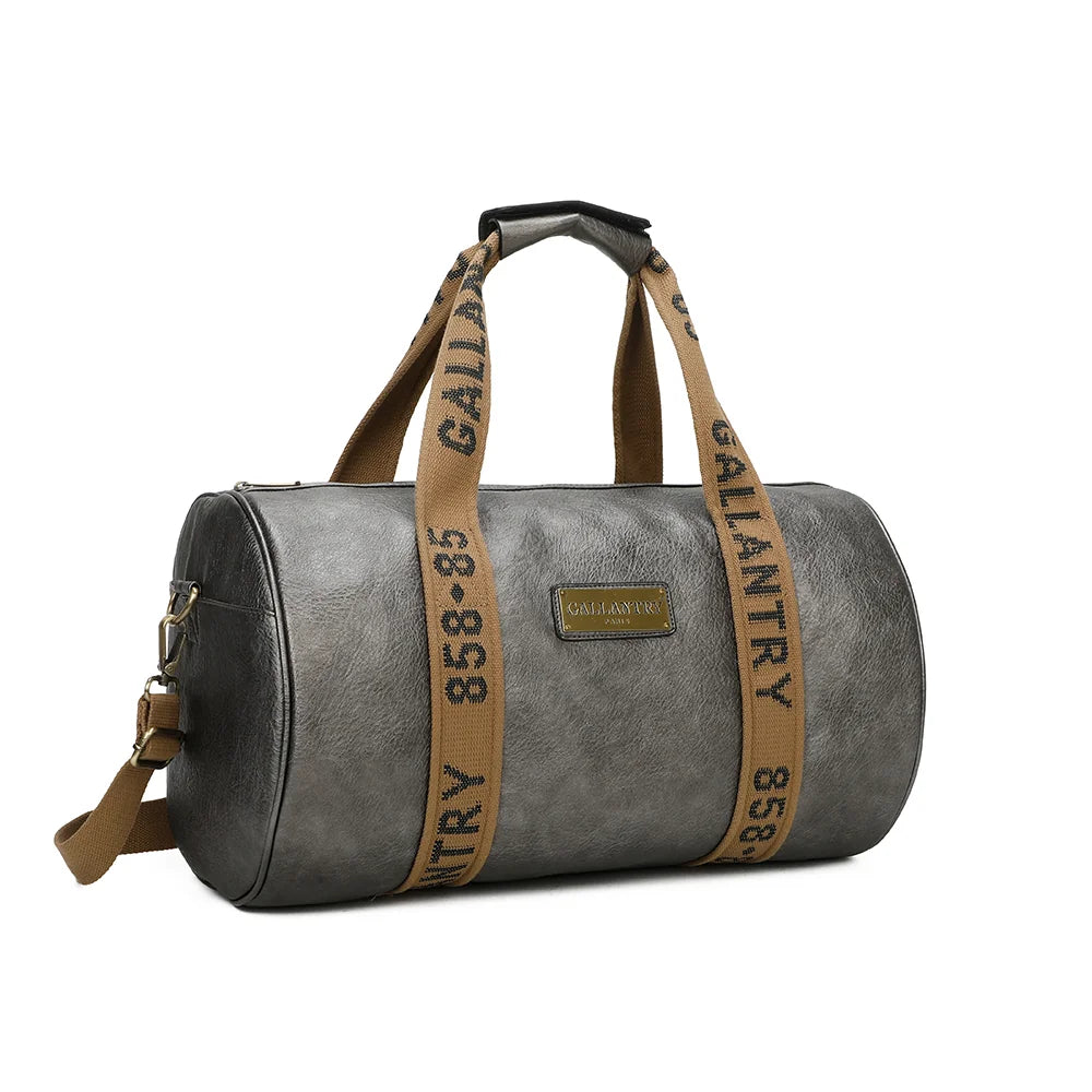 Polochon gris argenté de trois quarts : forme cylindrique, plaque logo dorée et bandoulière textile amovible – réf. Z-83049