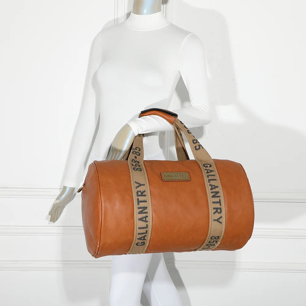 Sac de voyage Polochon marron porté à l’épaule par une femme grâce à sa bandoulière amovible – réf. Z-83049