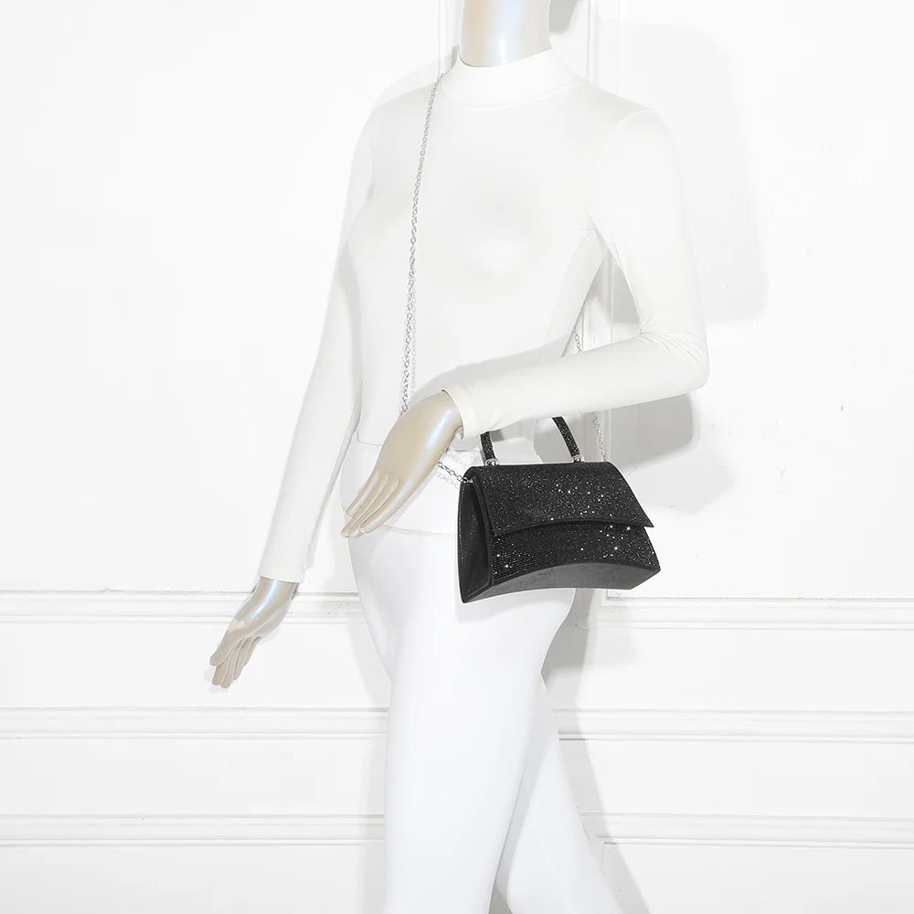 Sac de soirée Stellaire noir porté par une femme, à la main ou à l’épaule grâce à sa chaîne amovible – réf. LD-93004