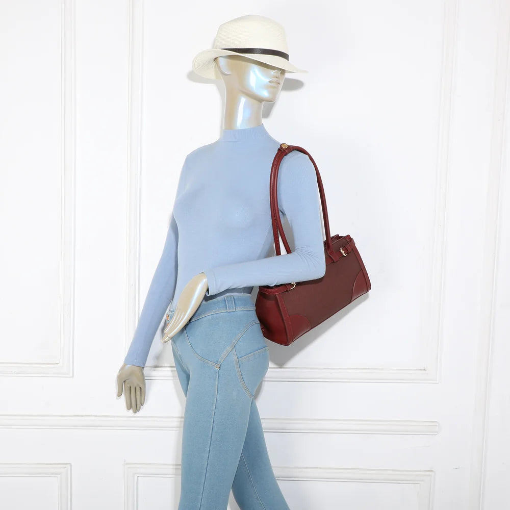 Sac Amarante bordeaux porté à l’épaule par une femme, format allongé qui se glisse sous le bras