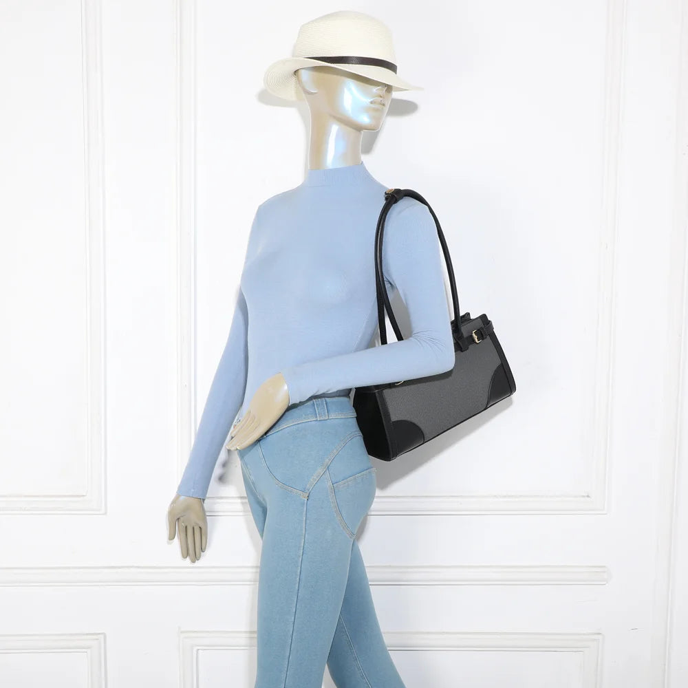 Sac Amarante noir porté à l’épaule par une femme, format allongé qui se glisse sous le bras