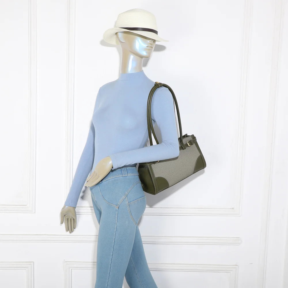 Sac Amarante vert porté à l’épaule par une femme, format allongé qui se glisse sous le bras