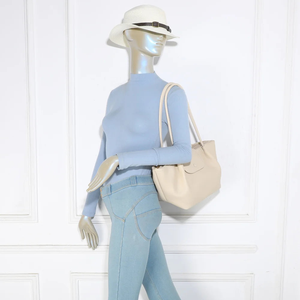 Sac Aura Soft beige porté à l’épaule par une femme, grâce à ses longues anses rondes de 30 cm – réf. R-2033
