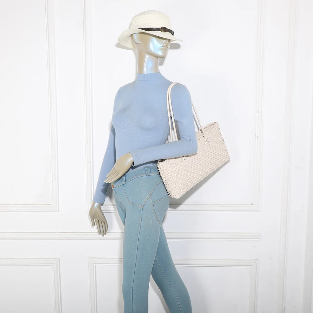 Sac cabas tressé Bréva beige porté à l’épaule par une femme, grâce à ses anses longues de 29 cm de hauteur – réf. DG-5822