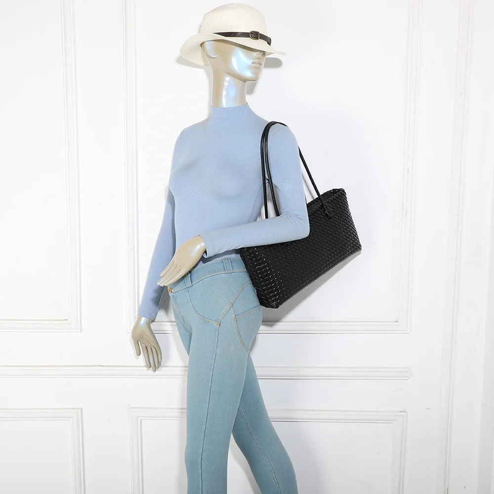 Sac cabas tressé Bréva noir porté à l’épaule par une femme, grâce à ses anses longues de 29 cm de hauteur – réf. DG-5822