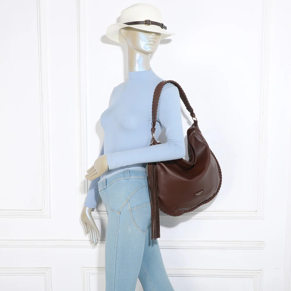 Sac Céleste café porté par une femme : anse tressée à l’épaule, pompon à franges le long de la silhouette – réf. JC-53006