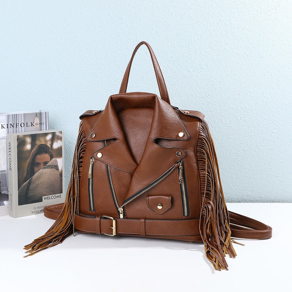 Sac Dakota Frangé marron à franges posé sur une table blanche devant des magazines et un mur bleu clair – visuel d’ambiance créé avec l’IA – Gallantry Paris
