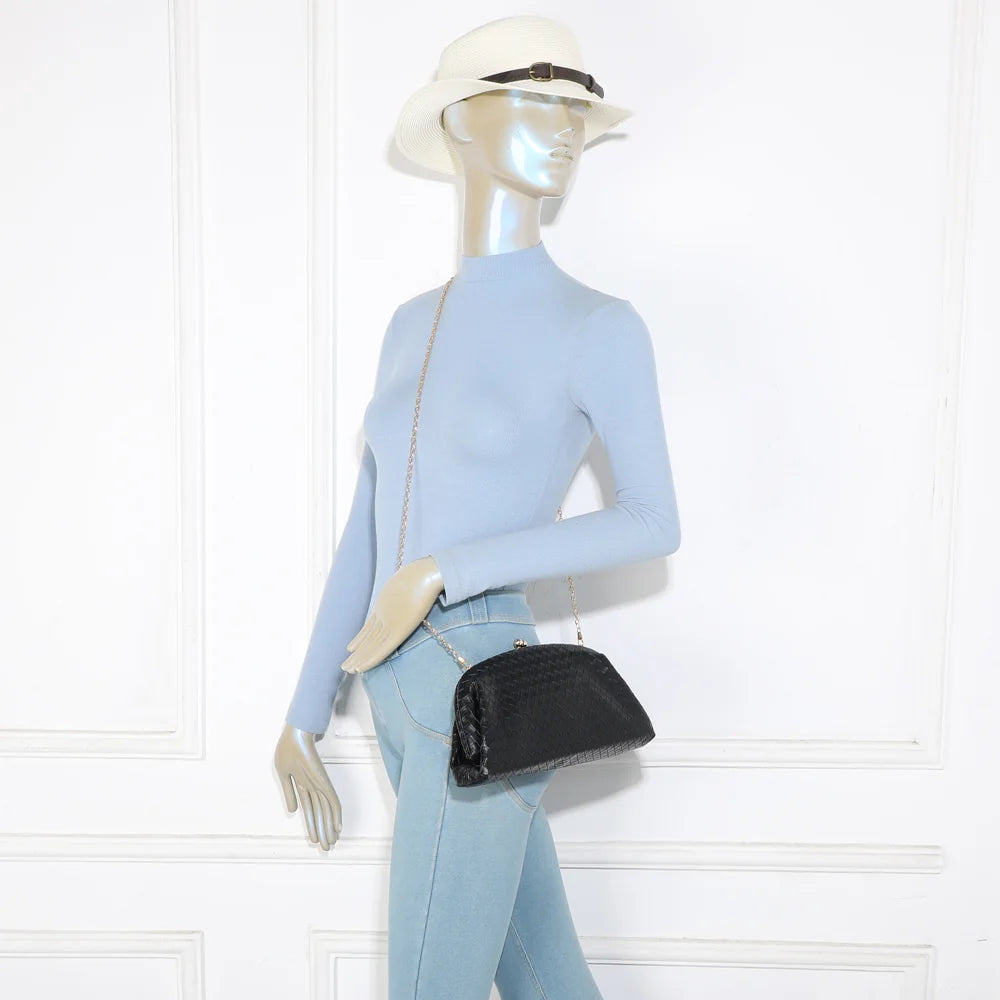 Pochette Doria noir portée par une femme, en bandoulière grâce à sa chaîne fine amovible – réf. LH-71005