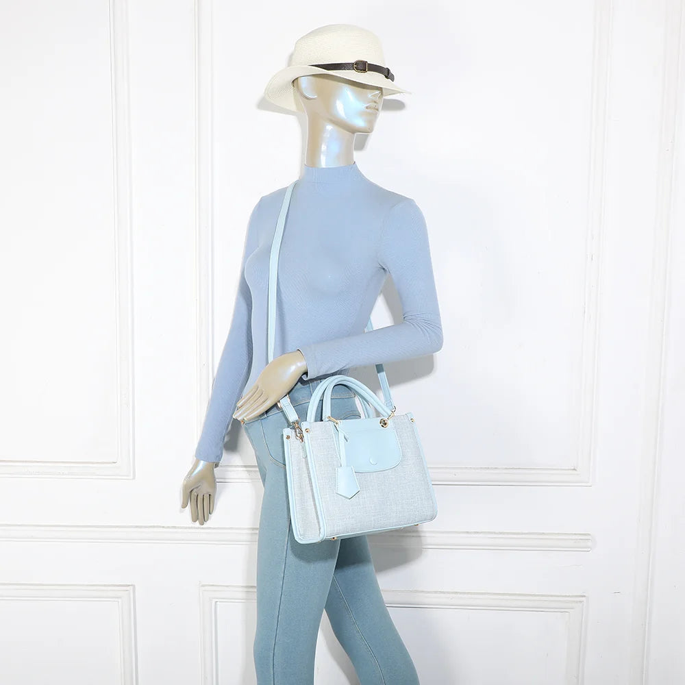 Sac Églantine bleu clair porté par une femme, à la main ou avec sa bandoulière amovible – réf. R-2036