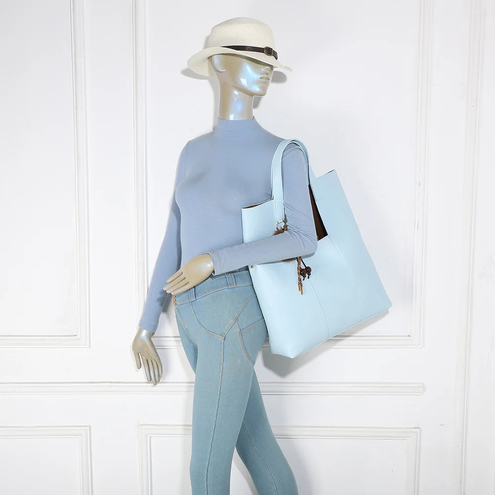 Sac cabas Erythéa bleu clair porté à l’épaule par une femme grâce à ses anses de 31 cm – réf. R-2027