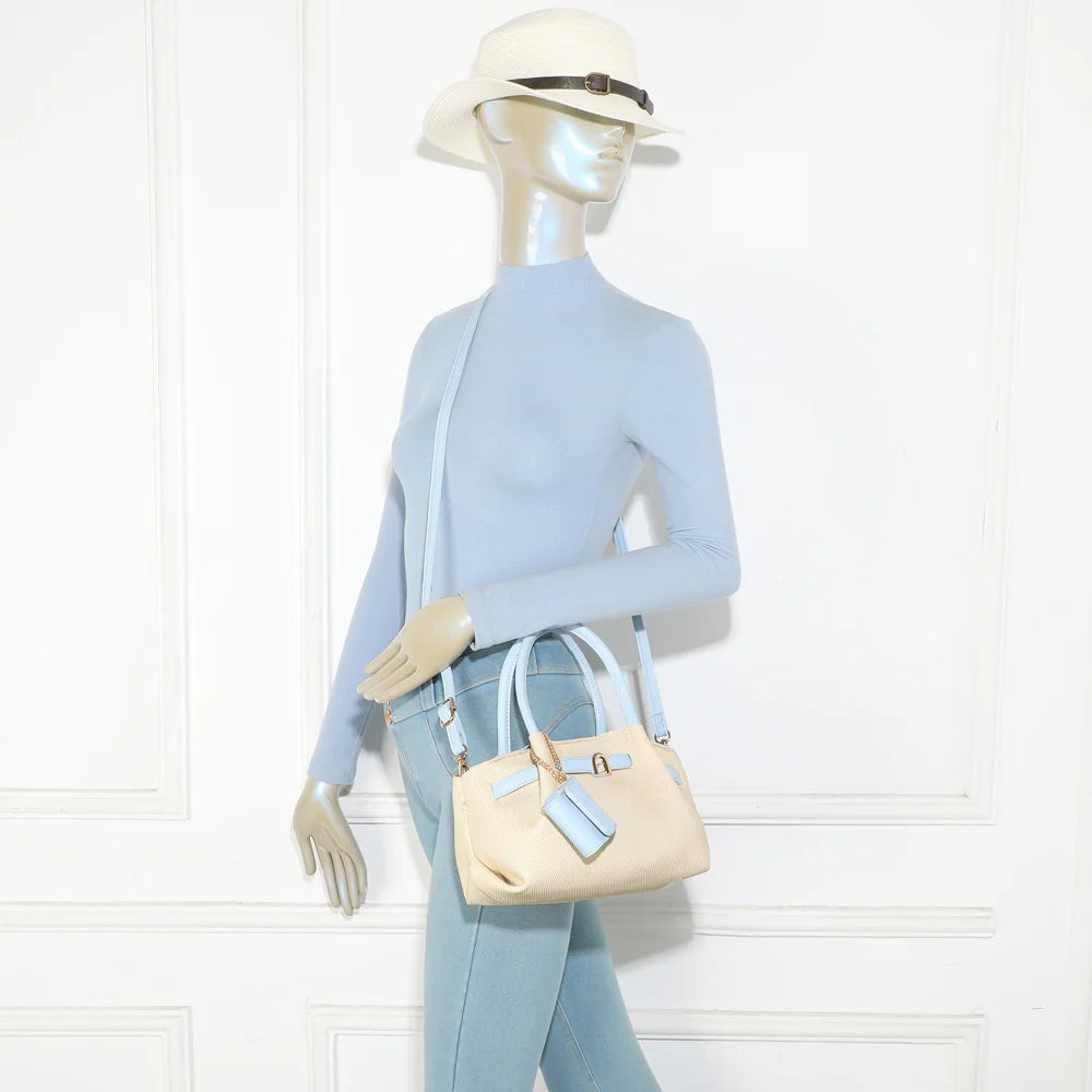 Sac Esmée bleu clair porté par une femme, à la main ou avec sa bandoulière amovible – réf. A-9156-1