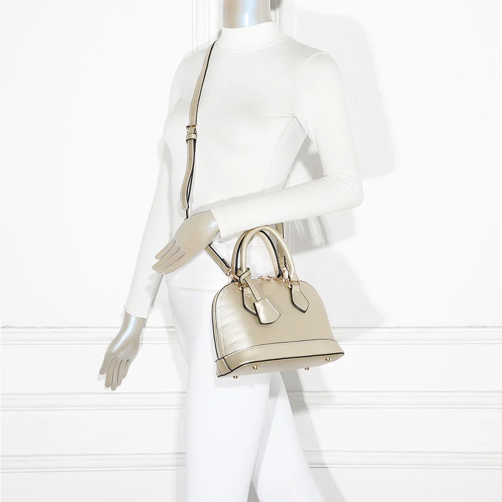 L'Éclat Mini bronze porté à la main par une femme, un petit sac bombé qui habille une tenue simple – réf. DQ-8596-5