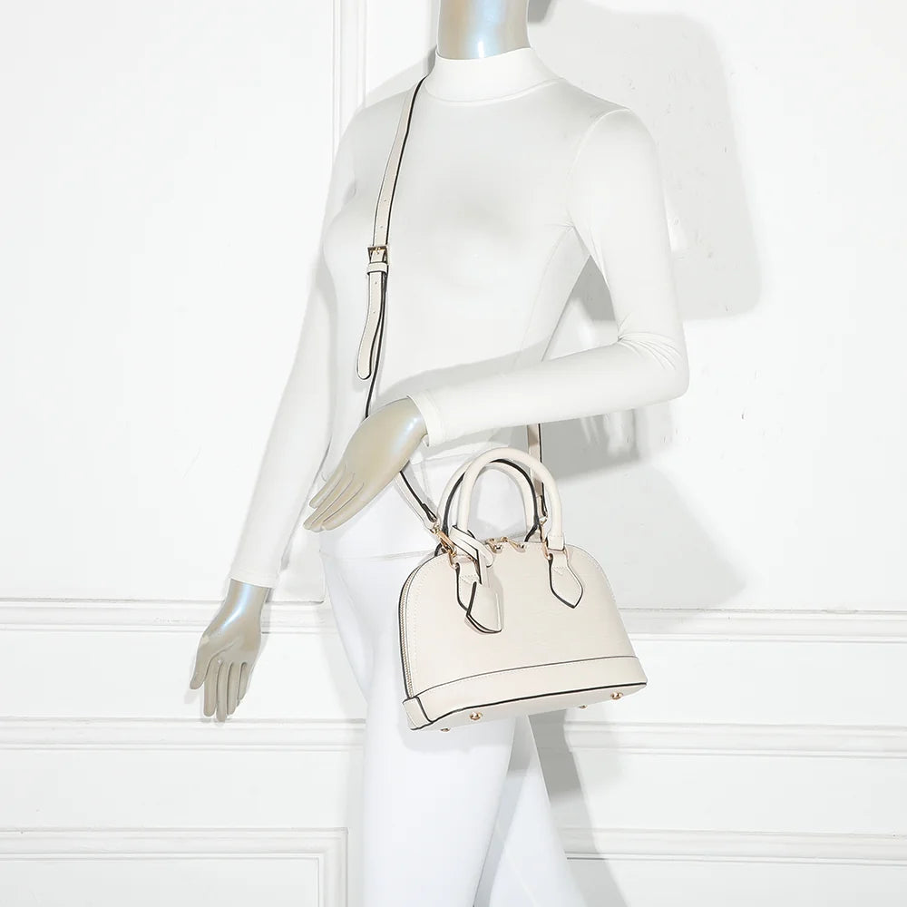 L'Éclat Mini or porté à la main par une femme, un petit sac bombé qui habille une tenue simple – réf. DQ-8596-5