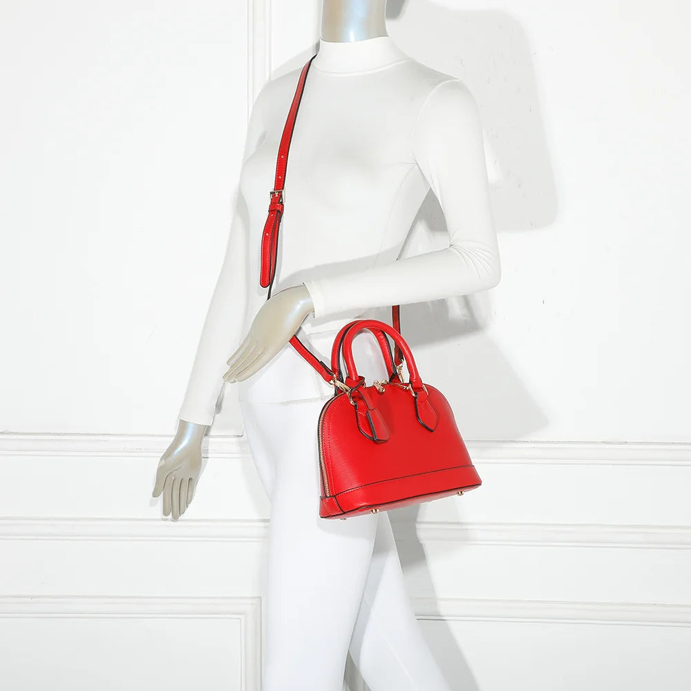 L'Éclat Mini rouge porté à la main par une femme, un petit sac bombé qui habille une tenue simple – réf. DQ-8596-5