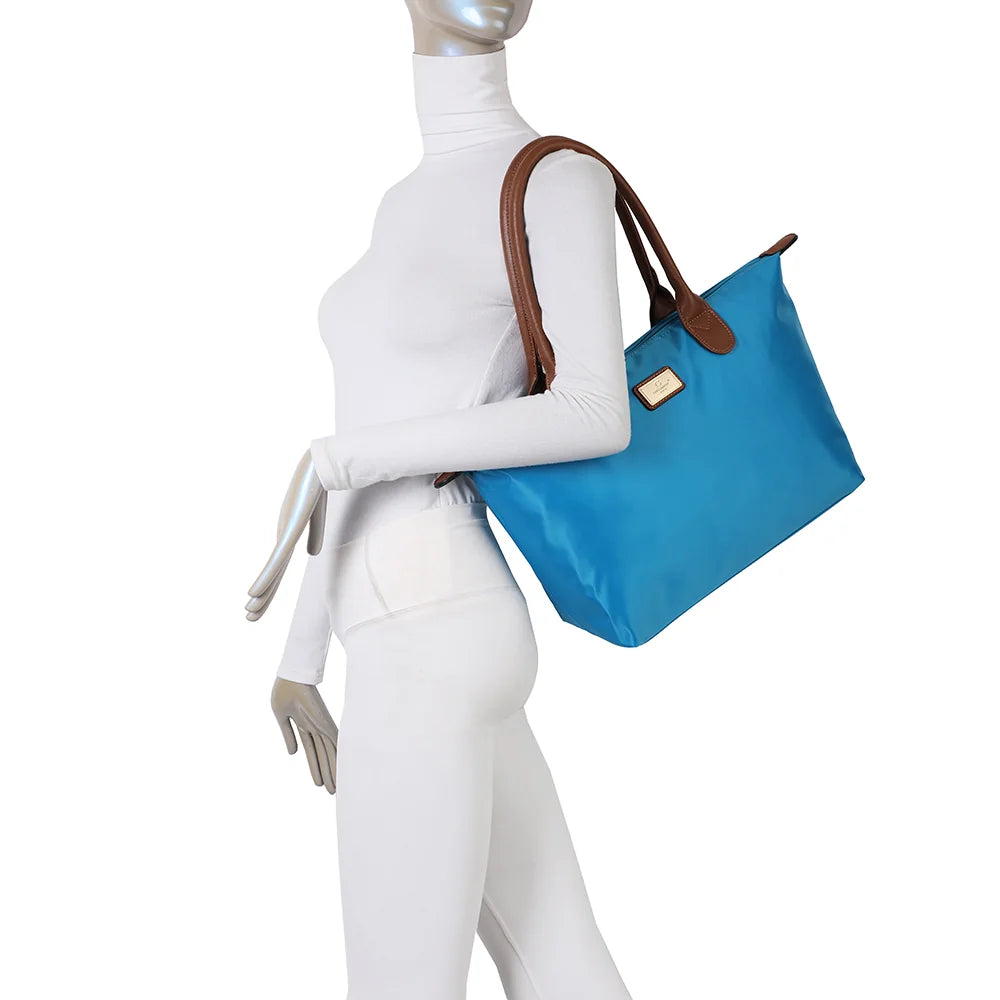 La Balade Medium bleu ciel portée par une femme : un sac cabas au format medium avec deux anses marron – réf. Z-03