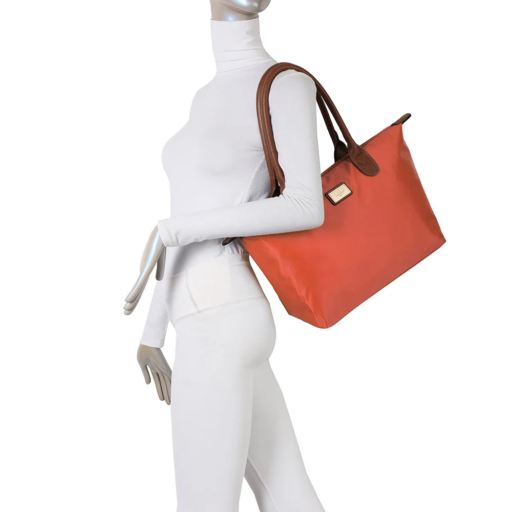 La Balade Medium orange portée par une femme : un sac cabas au format medium avec deux anses marron – réf. Z-03