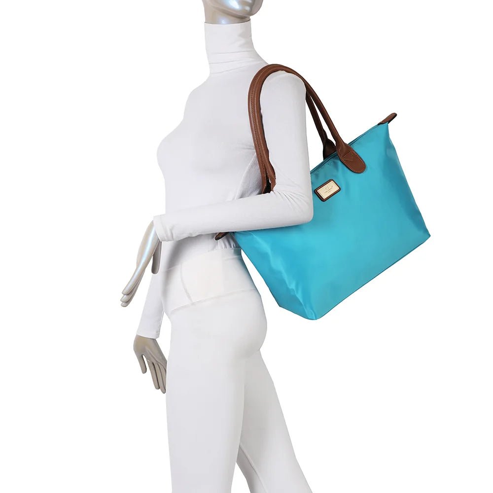 La Balade Medium turquoise claire portée par une femme : un sac cabas au format medium avec deux anses marron – réf. Z-03