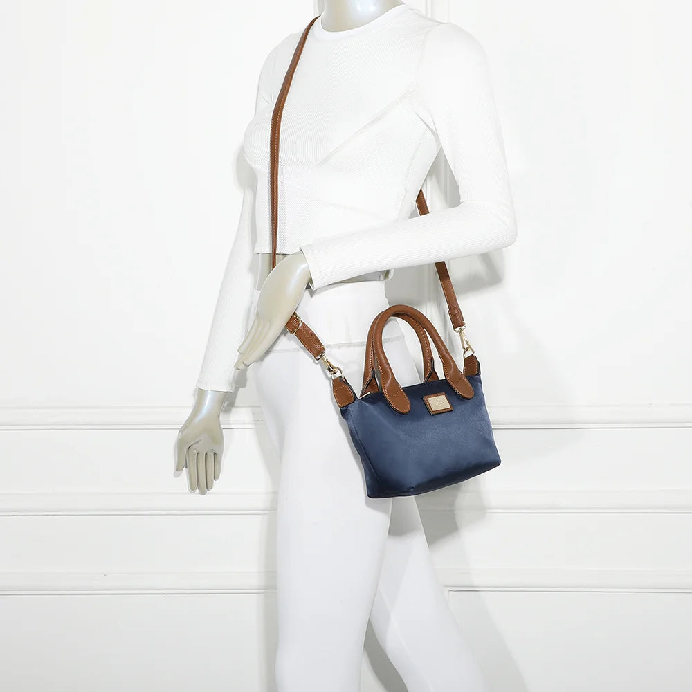Mini sac La Balade (Mini) marine porté par une femme, tenu à la main par ses anses courtes camel – réf. Z-05