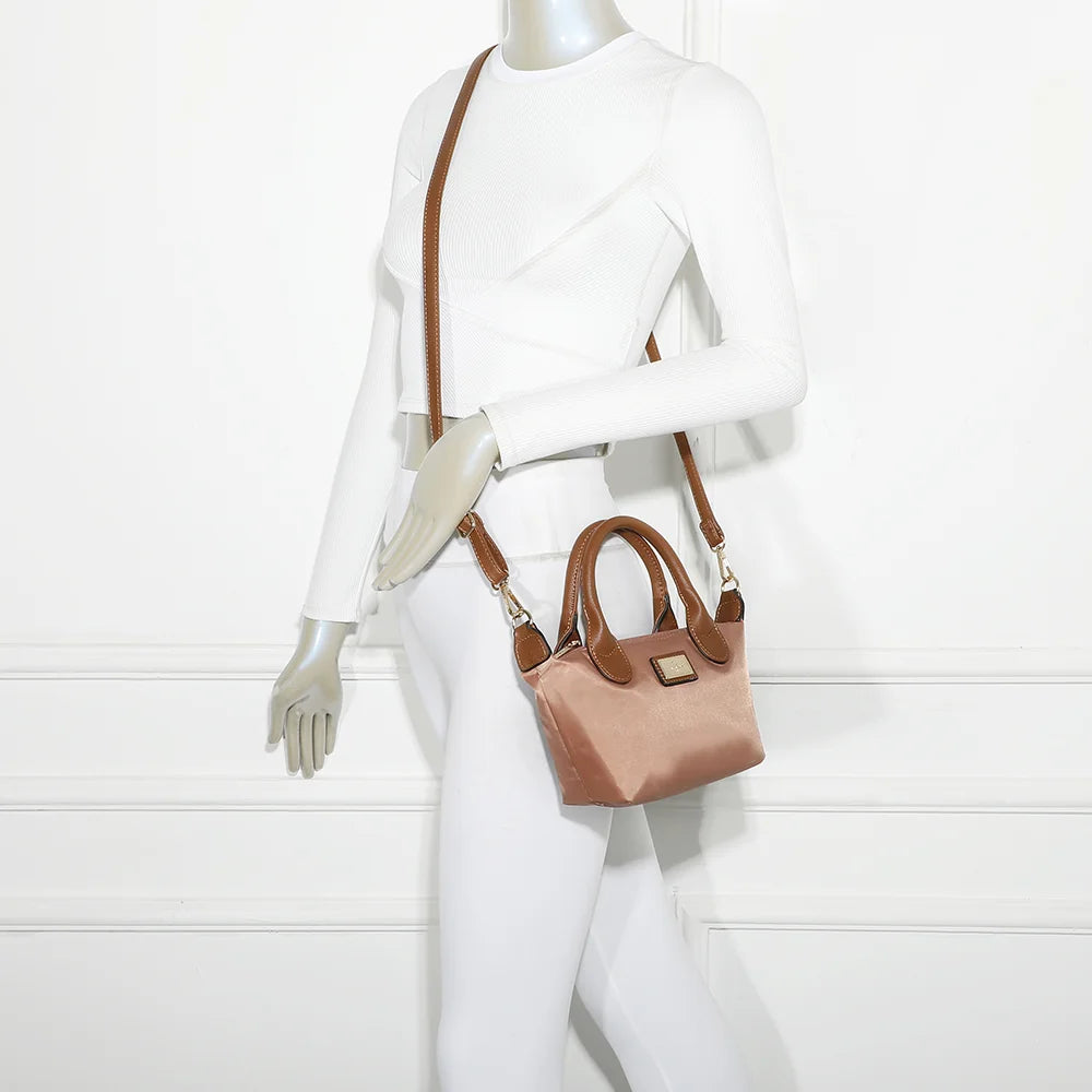 Mini sac La Balade (Mini) rose foncé porté par une femme, tenu à la main par ses anses courtes camel – réf. Z-05