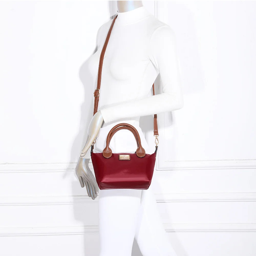 Mini sac La Balade (Mini) rouge foncé porté par une femme, tenu à la main par ses anses courtes camel – réf. Z-05