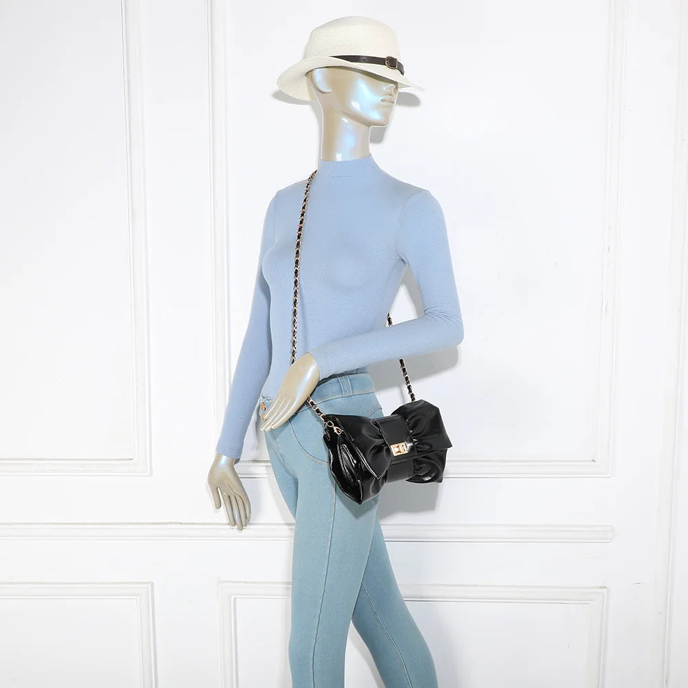Pochette La Diva noir portée par une femme : le nœud oversize illumine une tenue habillée – réf. DQ-37006