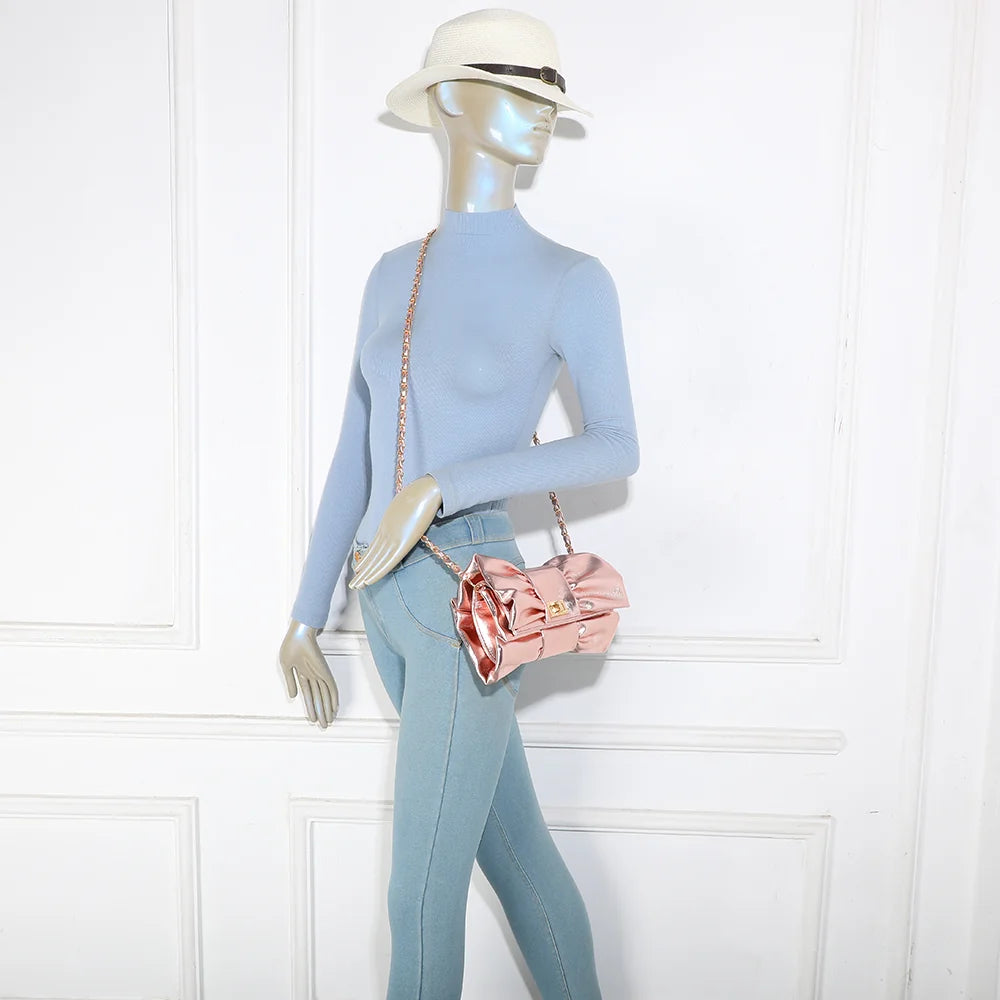 Pochette La Diva rose portée par une femme : le nœud oversize illumine une tenue habillée – réf. DQ-37006
