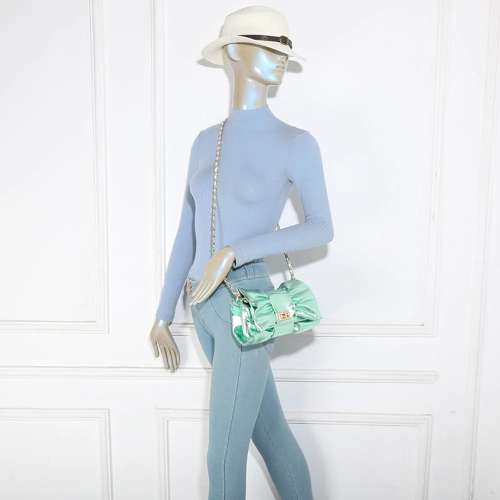 Pochette La Diva vert portée par une femme : le nœud oversize illumine une tenue habillée – réf. DQ-37006