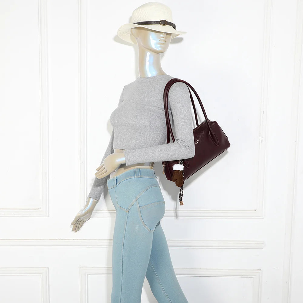 Sac à main La Linotte bordeaux porté par une femme, anses longues et breloque moufle en façade – réf. KJ-62100
