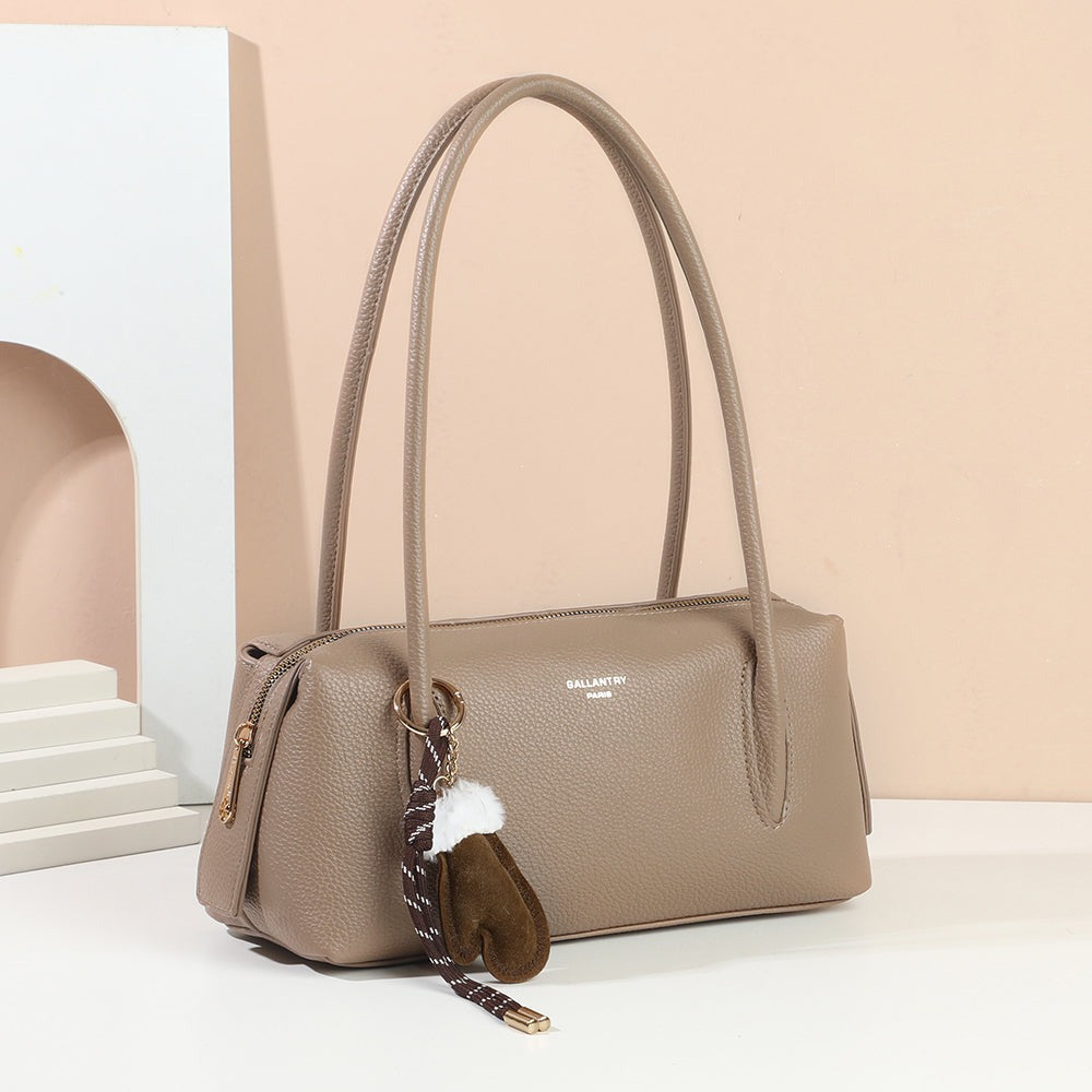Sac à main La Linotte taupe foncé et sa breloque moufle dans un décor – visuel d'ambiance créé avec l'IA – Gallantry Paris