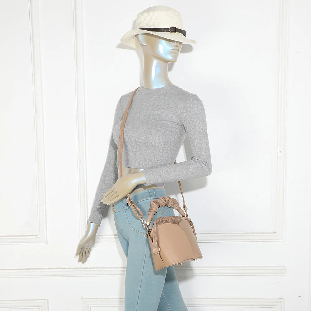 Sac La Nuvia taupe foncé porté par une femme, à la main par sa poignée froncée ou en bandoulière – réf. DQ-8727