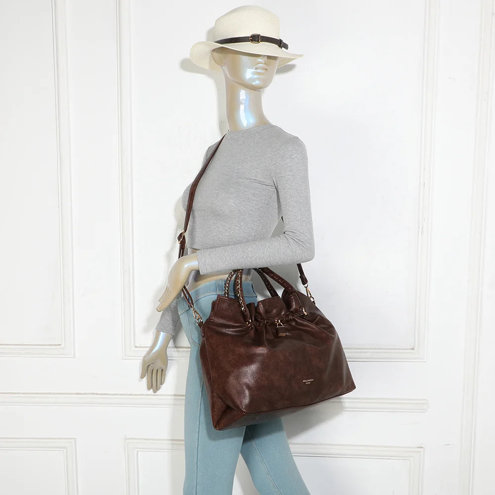 Sac La Régence marron foncé porté par une femme, à la main par ses anses à chaîne ou à l’épaule – réf. JC-53011