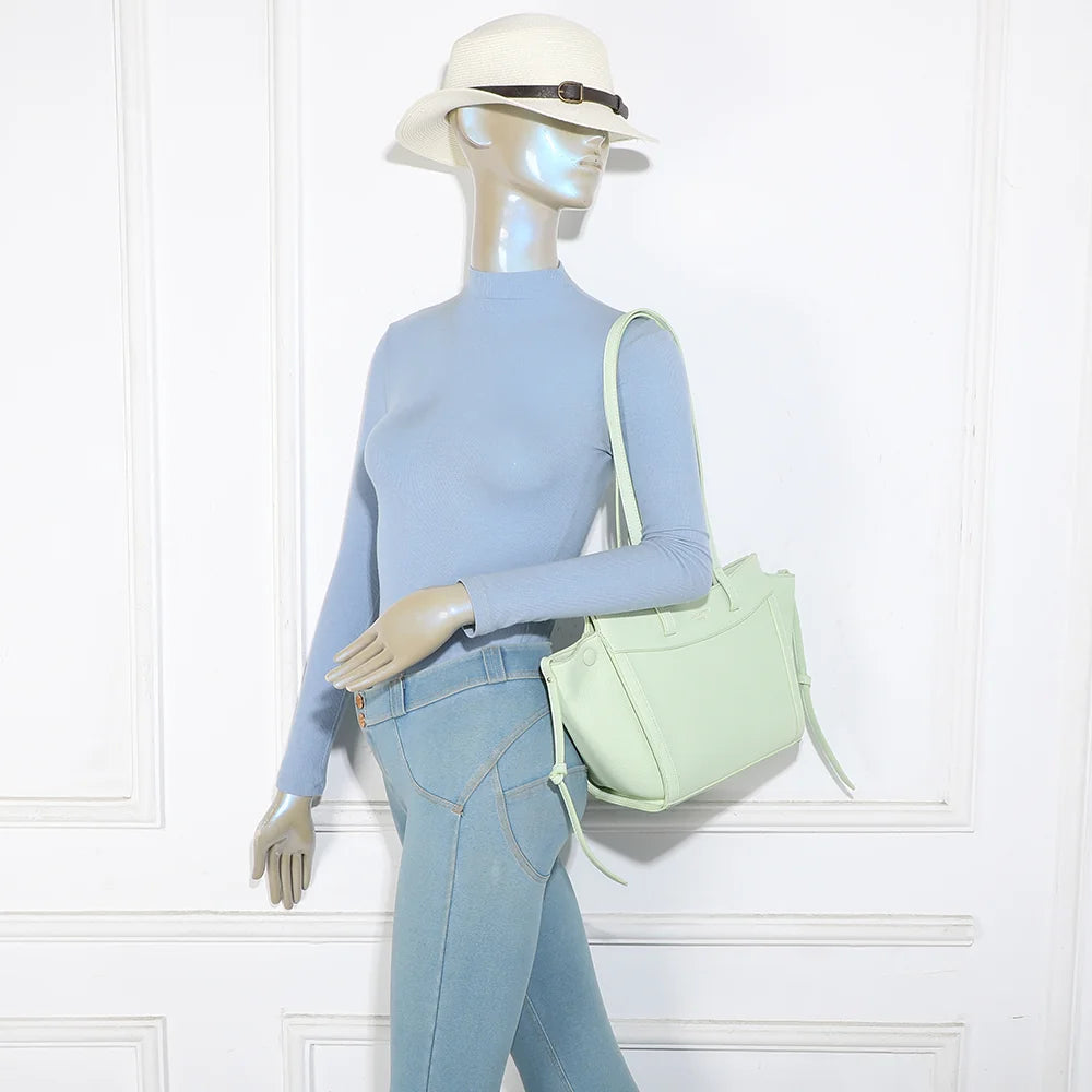Sac Laguna vert clair porté par une femme, à l’épaule grâce à ses longues anses de 34 cm – réf. R-2029