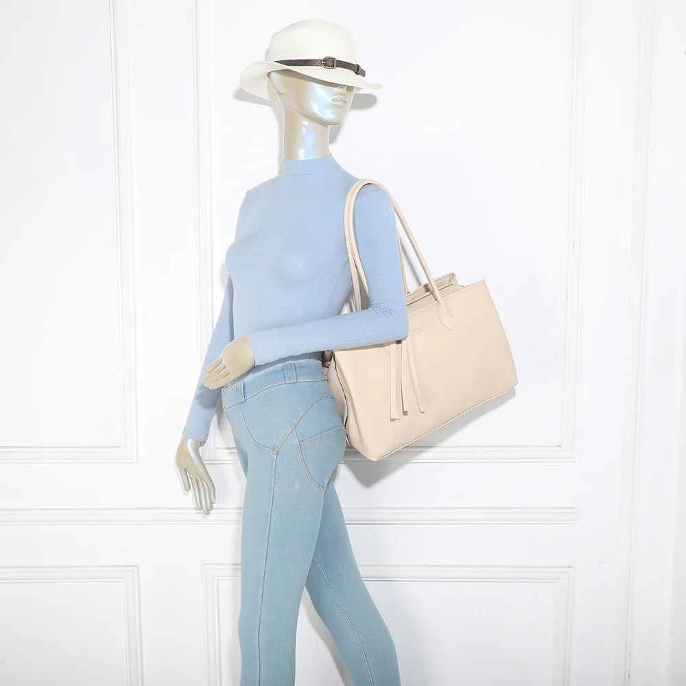 Sac Majestia beige porté à l’épaule par une femme grâce à ses deux longues anses de 29 cm – réf. M-9460-1
