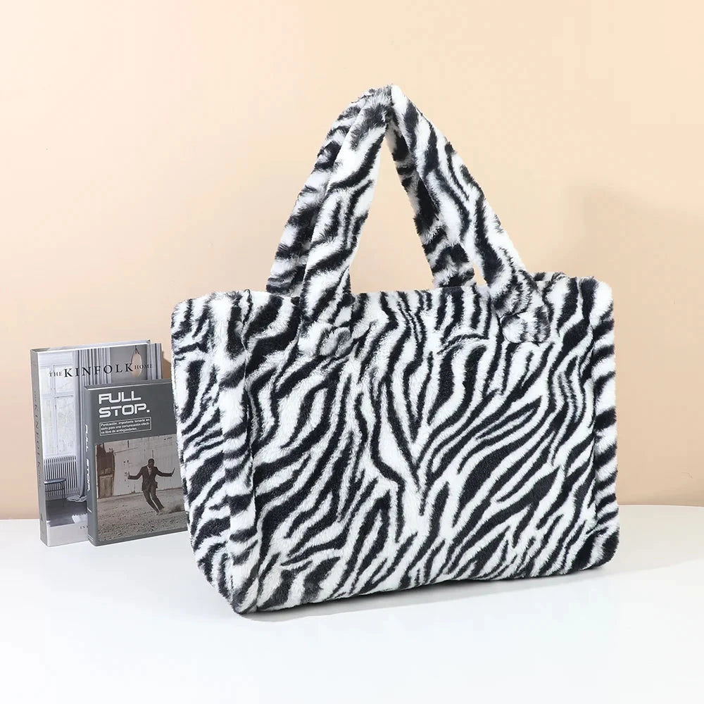Grand sac cabas femme Mélya zèbre en fausse fourrure posé devant des livres – visuel d'ambiance créé avec l'IA – Gallantry Paris