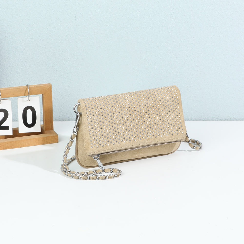 Pochette bandoulière Noctéa taupe cloutée mise en scène dans un décor – visuel d’ambiance créé avec l’IA – Gallantry Paris