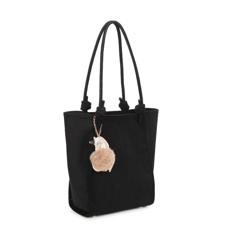 Noéva noir de trois-quarts : silhouette verticale, soufflets latéraux et bijou de sac pompon sur chaînette dorée – réf. M-9455