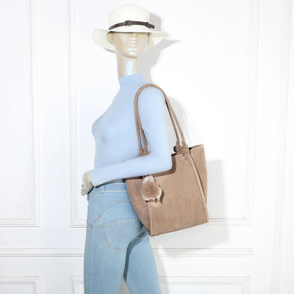 Sac cabas Noéva taupe porté à l’épaule par une femme, grâce à ses deux longues anses nouées – réf. M-9455